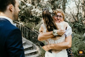At Château de Barbegal in Arles en Provence, the mother embraces the bride in her arms after a touching ceremony, while the groom looks on.